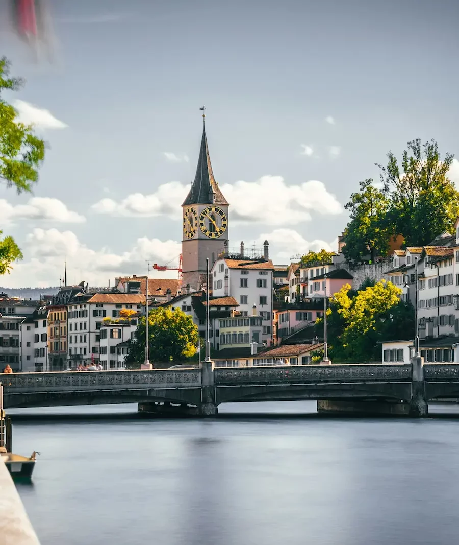 View of the Limmat River and historic Münsterbrücke bridge with Zurich Old Town churches in the background.