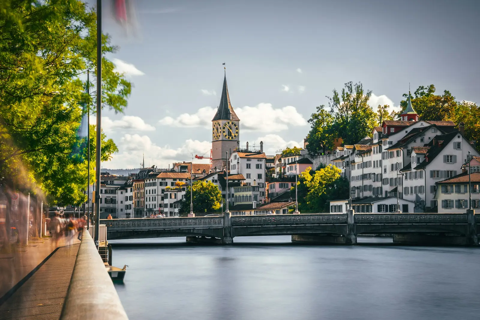 View of the Limmat River and historic Münsterbrücke bridge with Zurich Old Town churches in the background.